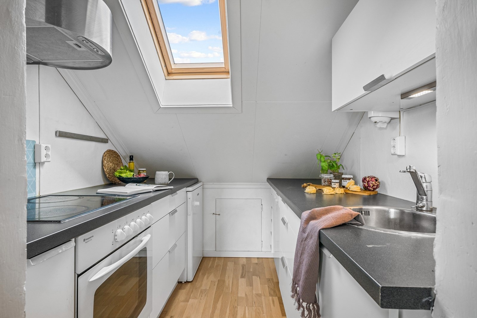 Fint og tidløst kjøkken med glatte fronter i hvit utførelse. Lagring i kneloft. Galleribilde