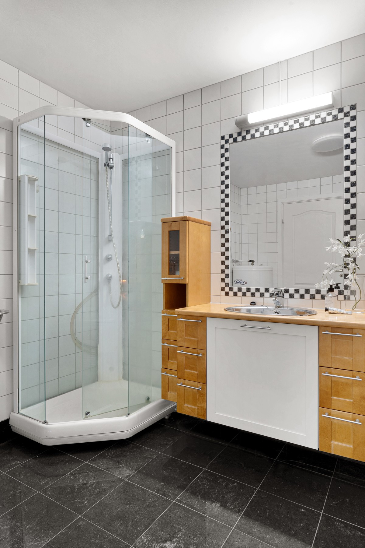 Badet er også innredet med dusjkabinett, servant og toalett