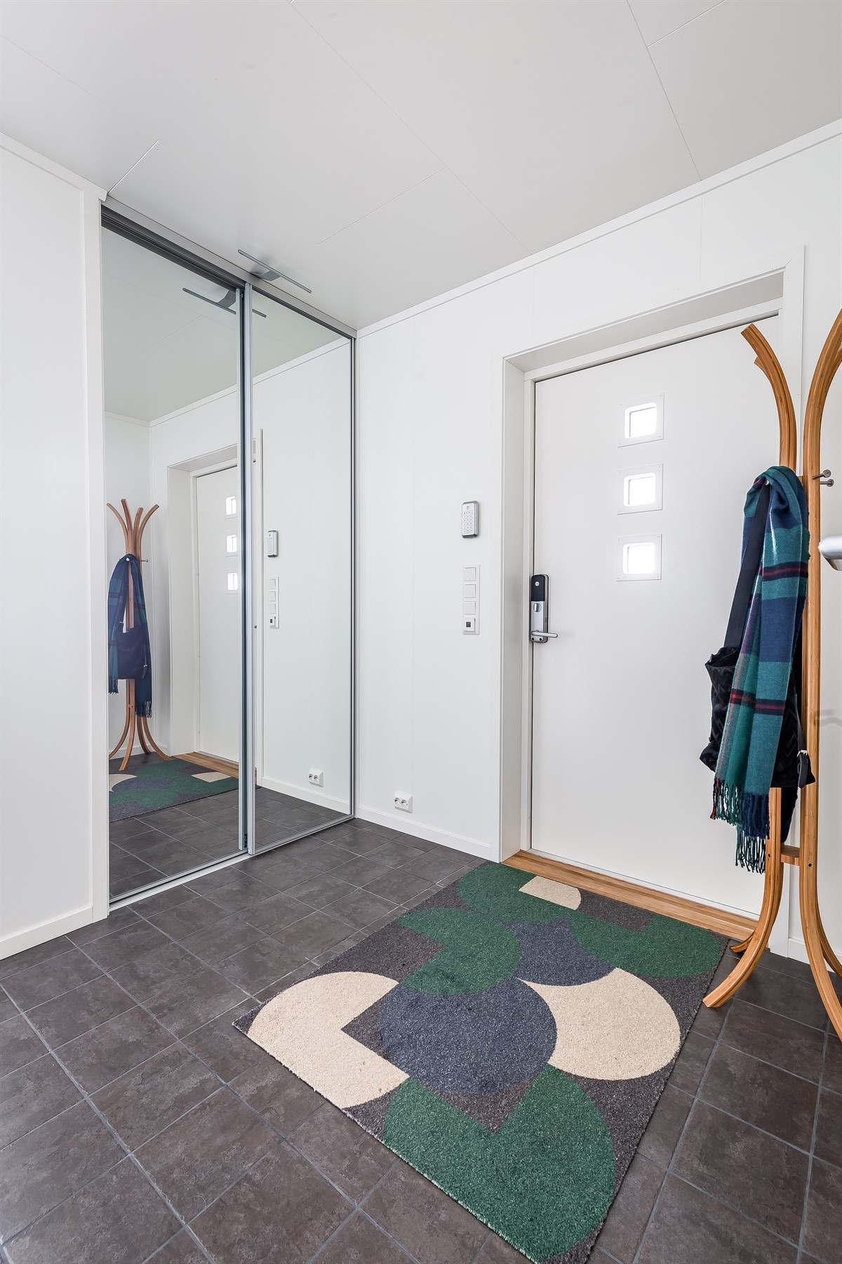 Flislagt inngangsparti og skyvedørsgarderobe med store speil