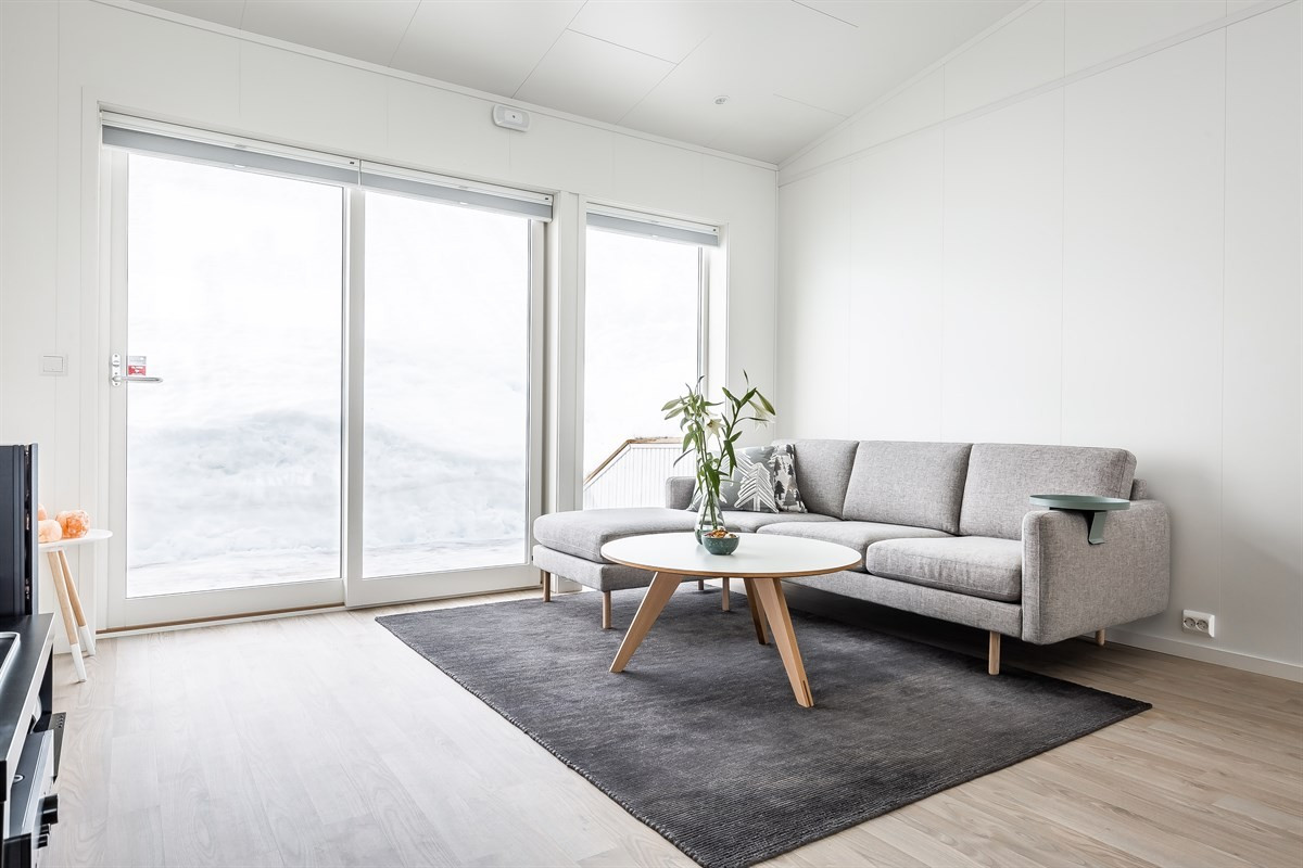 Romslig stue med store glassflater og skyvedør ut til terrasse på baksiden