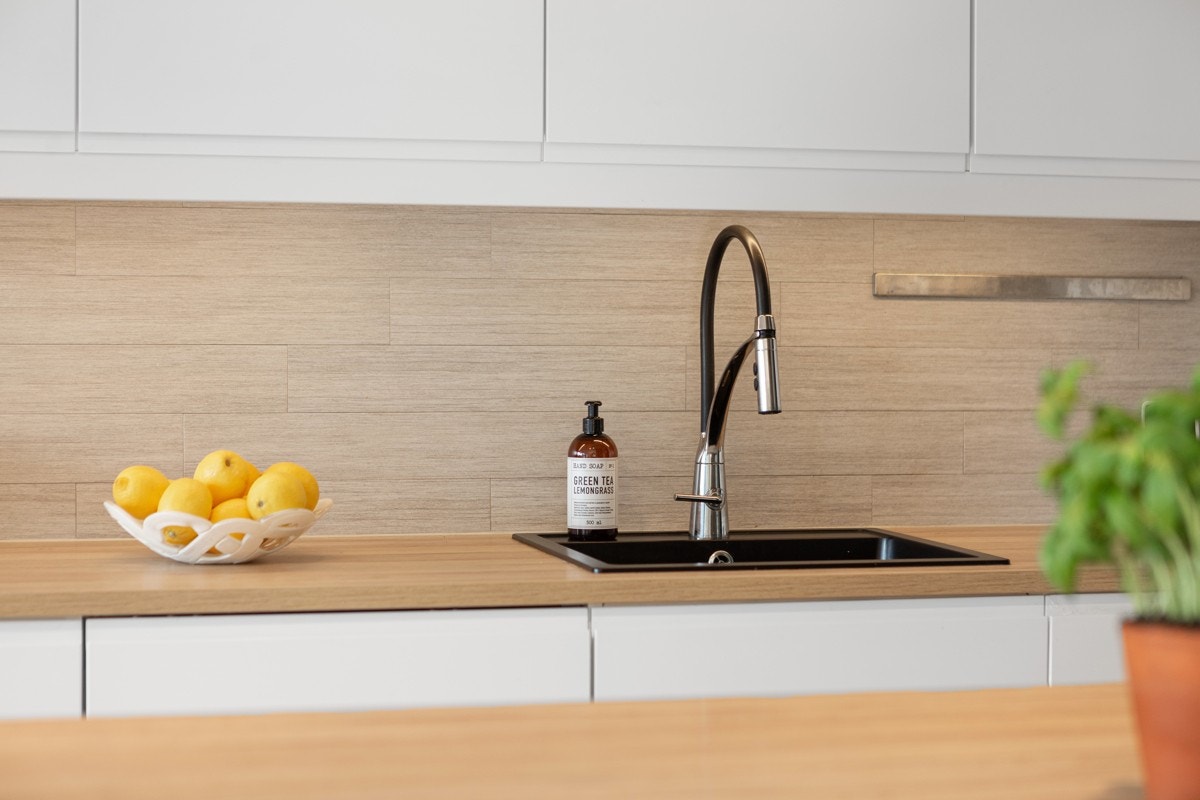 Den tidsmessige, takhøye kjøkkeninnredningen har hvite, glatte fronter med integrerte håndtak, trehvite laminatbenkeplater, og nedfelt oppvaskkum i komposittmateriale. Galleribilde