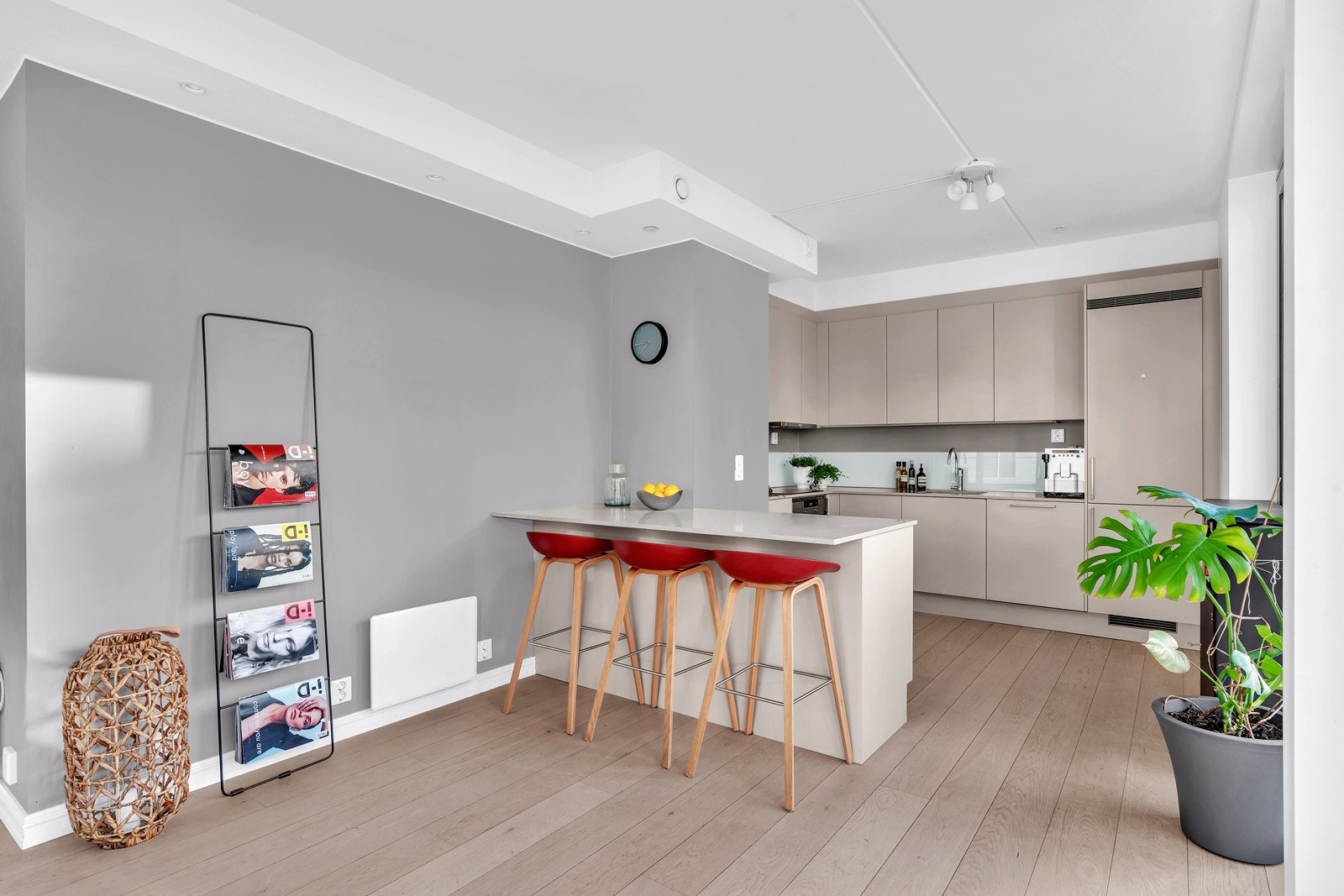 Kjøkkenet er innredet med lyse glatte fronter, benkeplate i stein og kjøkkenøy Galleribilde