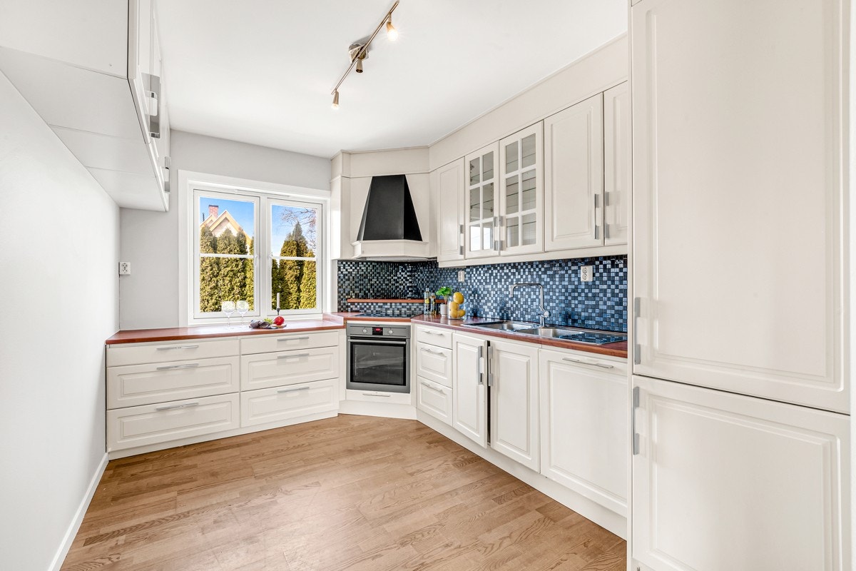 2.etasje | Innredningen fra 2011 har hvite, profilerte fronter, vitrineskap og laminatbenkeplate med dobbel oppvaskkum. Galleribilde