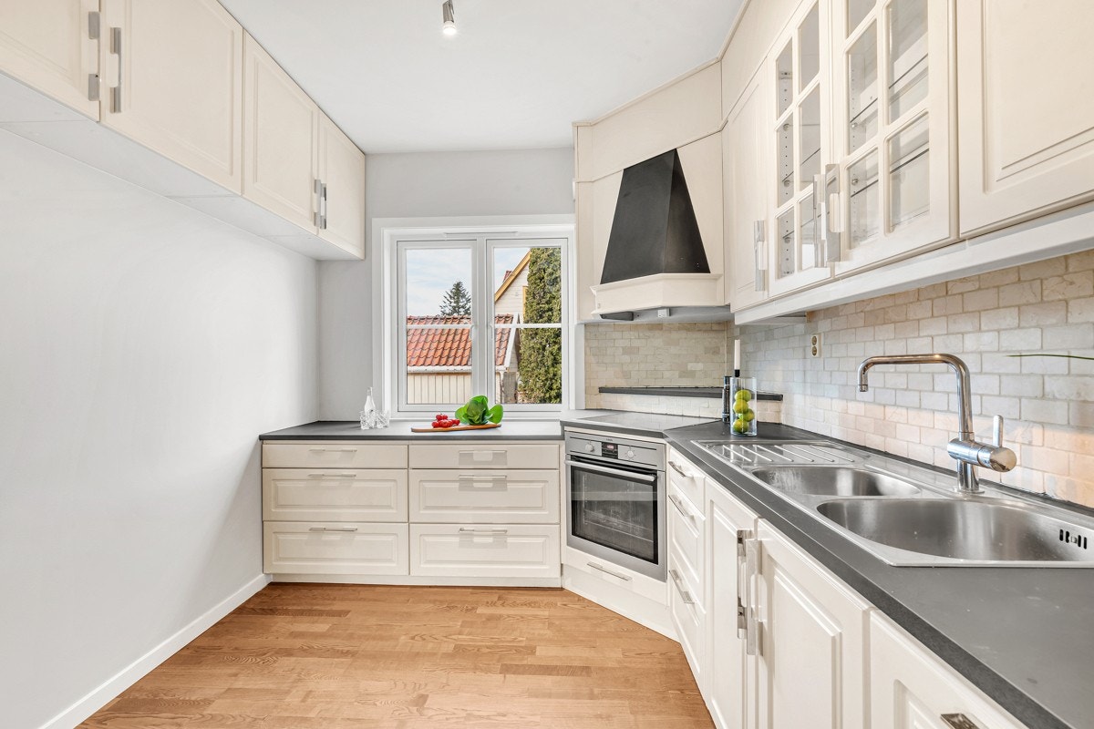 1.etasje | Innredningen fra 2011 har hvite, profilerte fronter, vitrineskap og laminatbenkeplate med dobbel oppvaskkum. Galleribilde