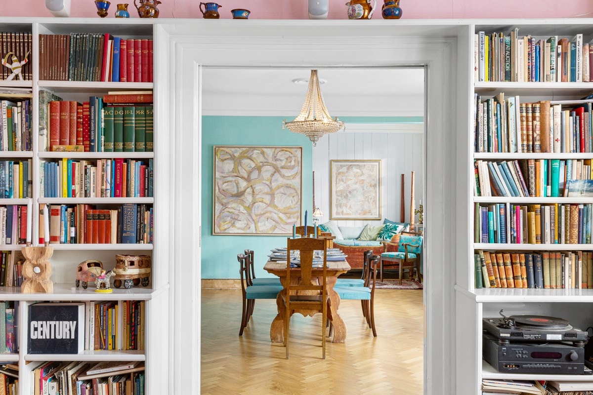 Plassbygde bokhyller omslutter den brede åpningen mot spisestuen. En skyvedør gjør at stuene kan gjøres mer private. Galleribilde