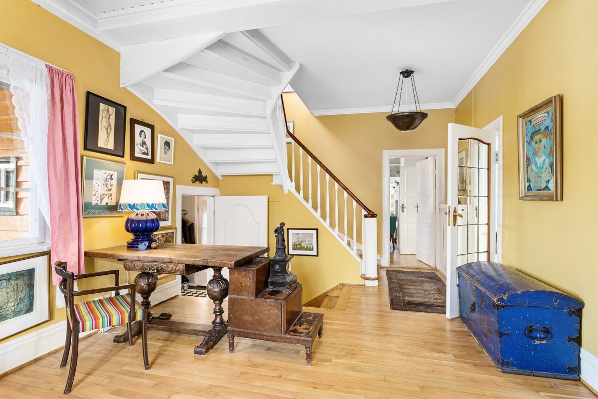 Gangen i første etasje har adkomst til kjøkkenet og peisestuen. En malt tretrapp svinger seg videre oppover i etasjene. Galleribilde