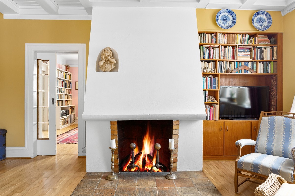 En monumental peis forsterker det herskapelige preget. Det er plassbygde bokhyller og skyvedør inn til stuen. Galleribilde