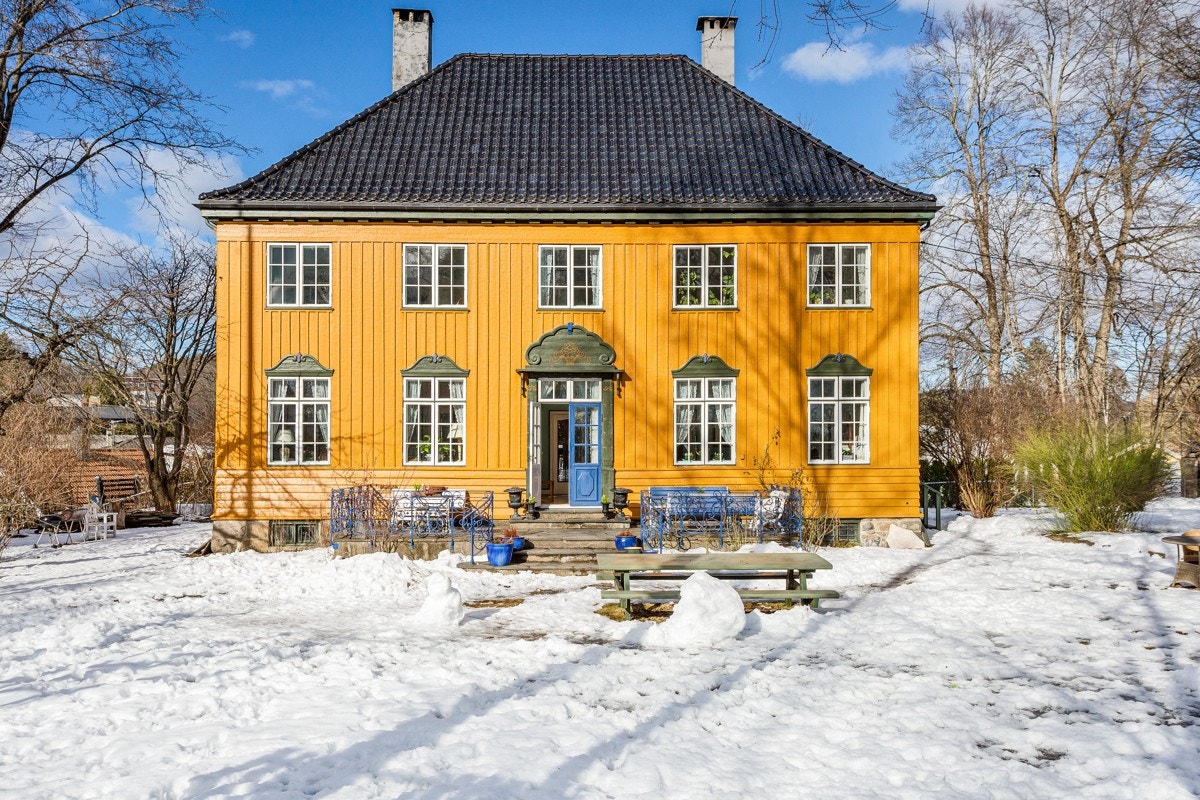 Villaen er malt i en varm, gul okerfarge som lar huset skinne. Gulfargen står nydelig til blå og olivengrønne detaljer. Galleribilde