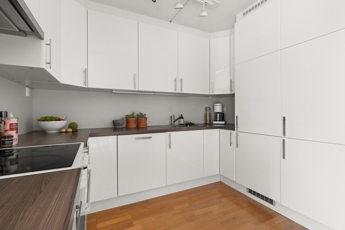 Tidløs og stilig kjøkkeninnredning med hvite fronter og laminat benkeplate. Galleribilde