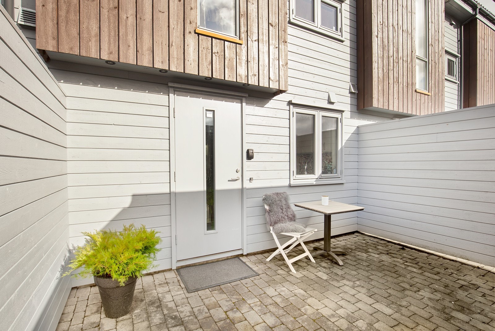 Flott inngangsparti med belegningsstein i gårdsrom og spotter over inngangsdør Galleribilde