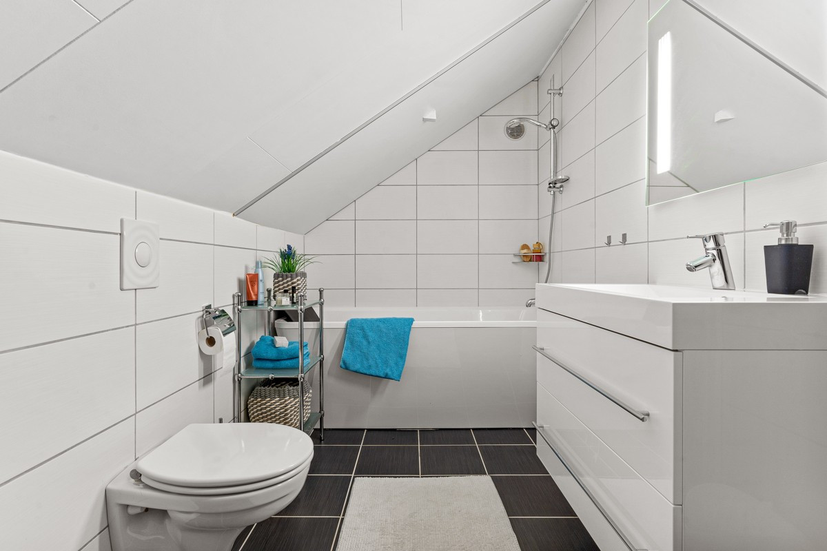 Lyst og fint baderom med dusj/badekar, wc og servantskap
