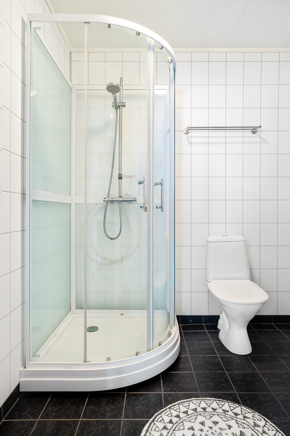 Her inne finner du gulvmontert toalett, dusjkabinett, servant med speil og opplegg for vaskemaskin