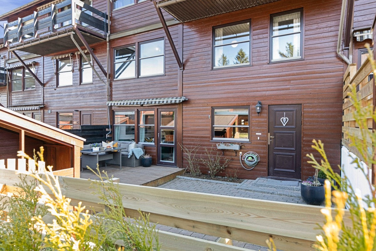 Fra en rolig, bilfri vei er det direkte adkomst til boligen som har inngangsparti fra bakkeplan. Det første dere møter er et steinbelagt inngangsparti med lekeplass på ca. 26.m². Galleribilde