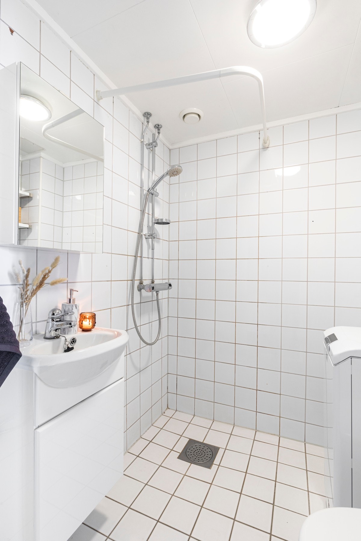 Leiligheten har et lyst flislagt baderom med slett innredning og lyse fliser. Galleribilde