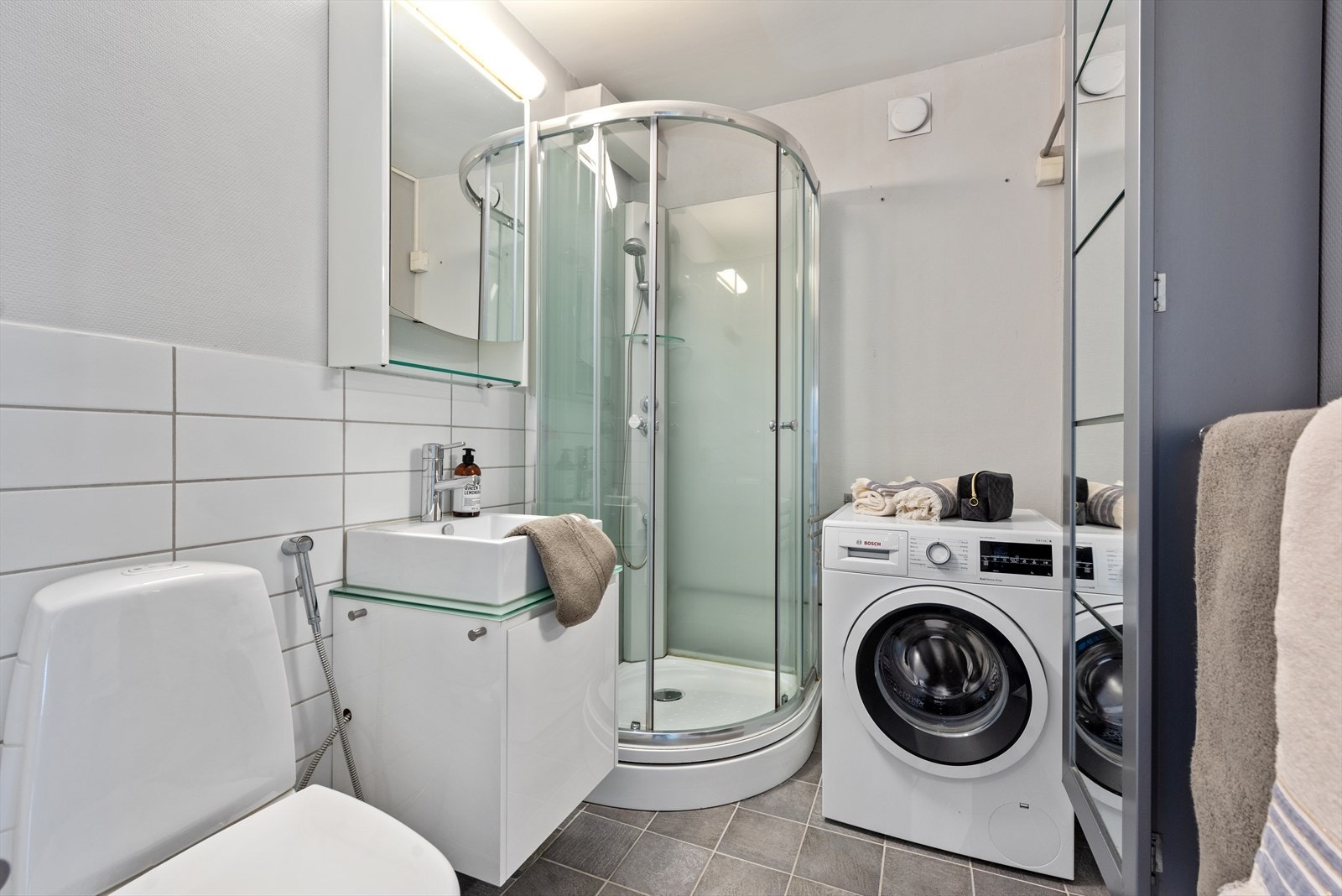 Badet er innredet med dusjkabinett, servant, klosett og opplegg for vaskemaskin. Galleribilde