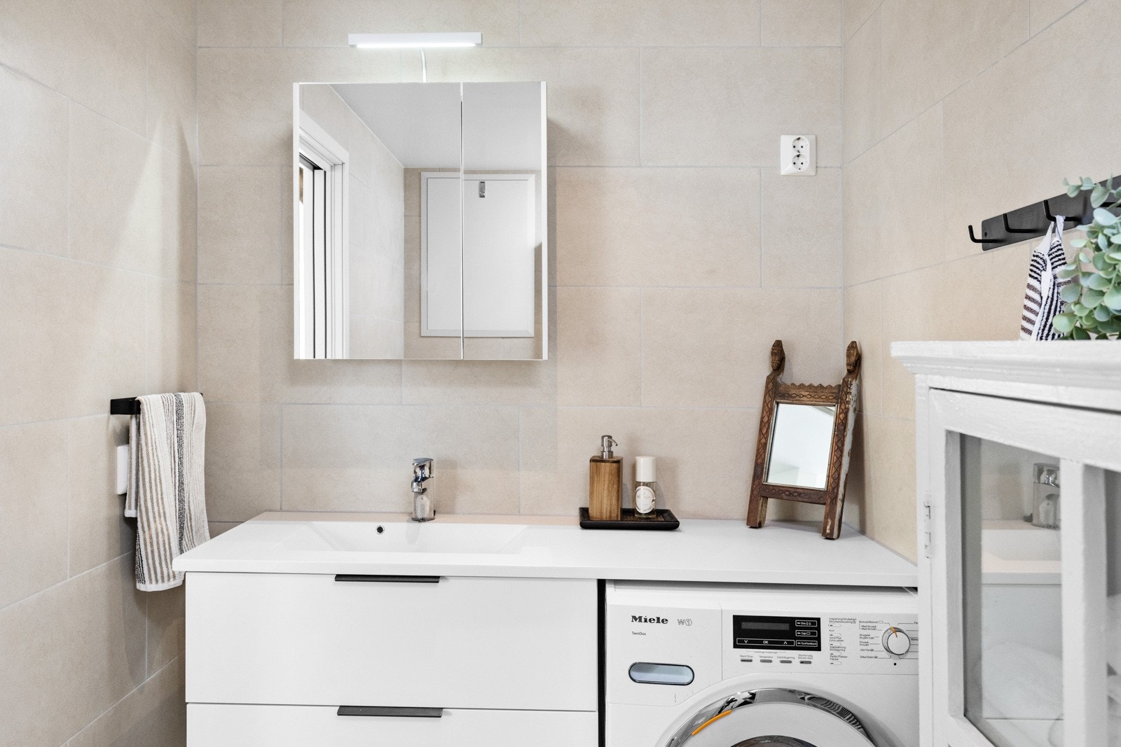Badet er flislagt og har varmekabler i gulv. Lekkert og praktisk innredning bestående av benkeskap og veggskap med speilfronter og belysning over servant. Galleribilde