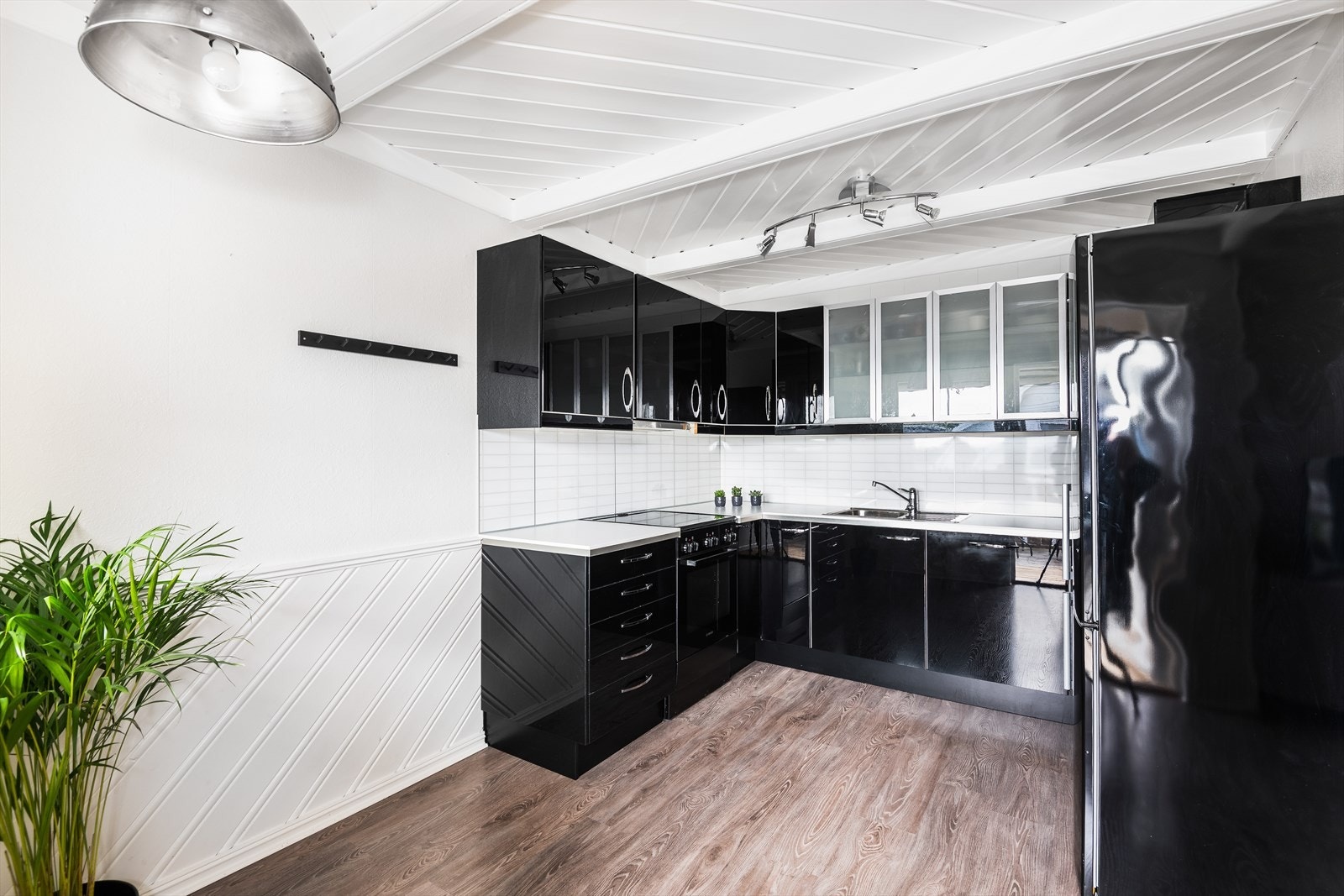 Lekkert kjøkken med sort innredning med glatte fronter og laminert benkeplate med kitchenboards over Galleribilde