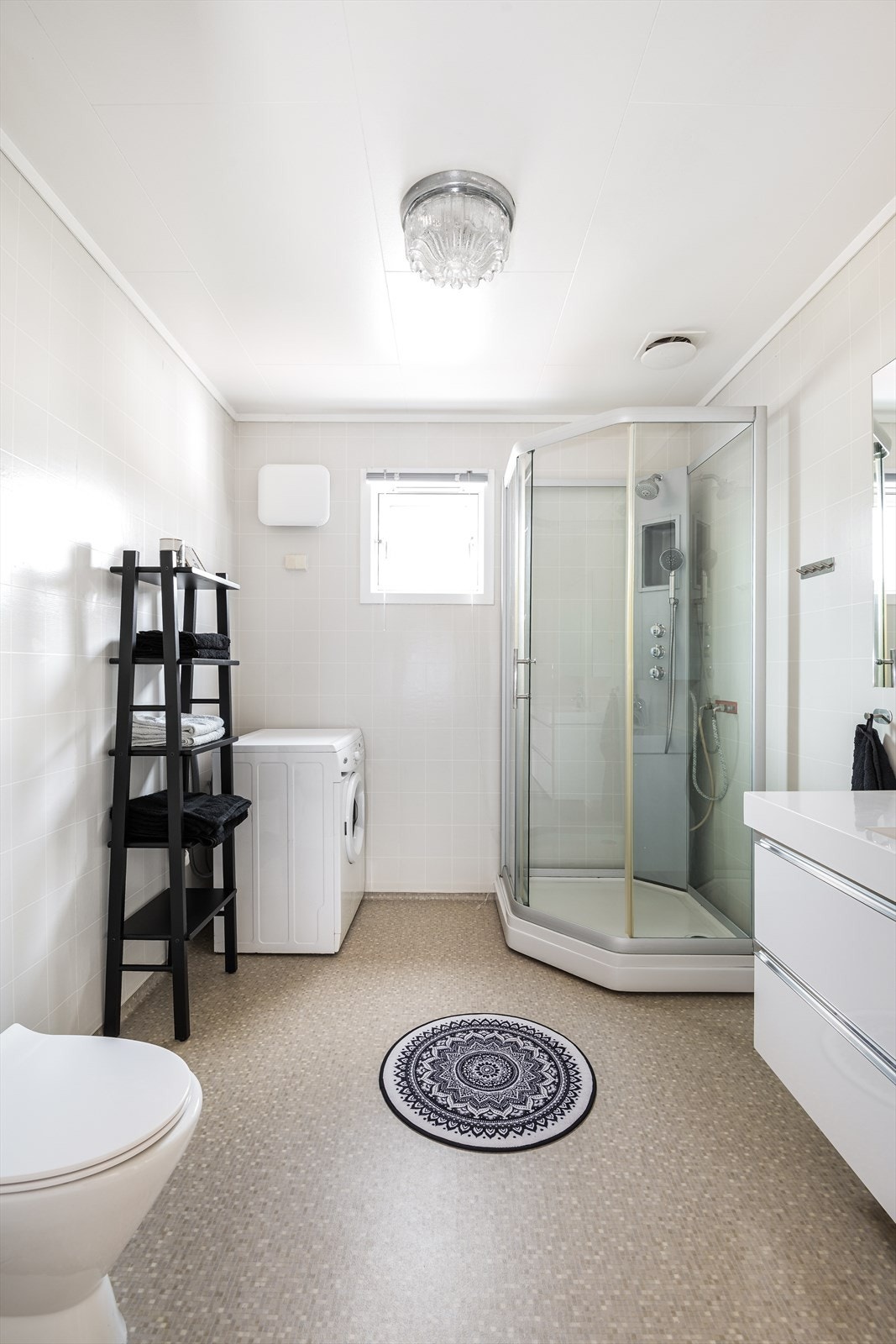 Badet inneholder dusjkabinett, toalett, hvit servant med underskuffer, stort overskap med lys og speil. Det er opplegg for vaskemaskin Galleribilde