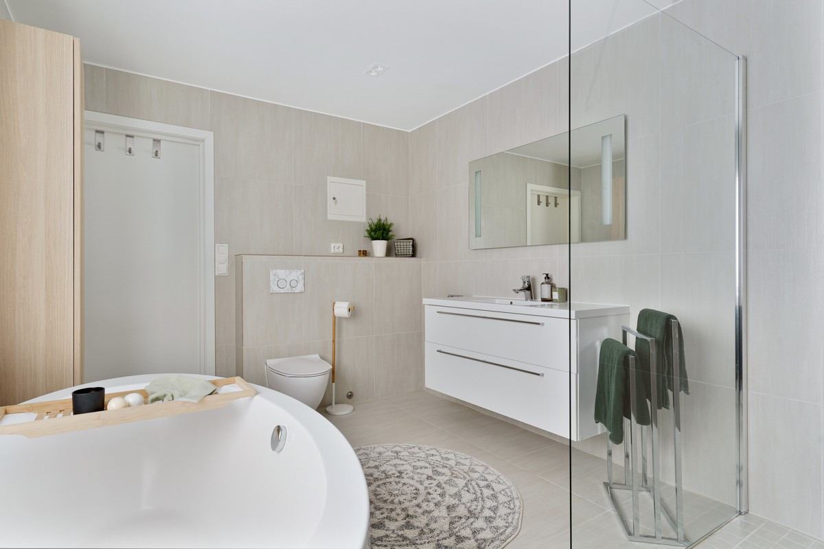 Badet har stor servant, dobbel dusj, badekar og vegghengt toalett