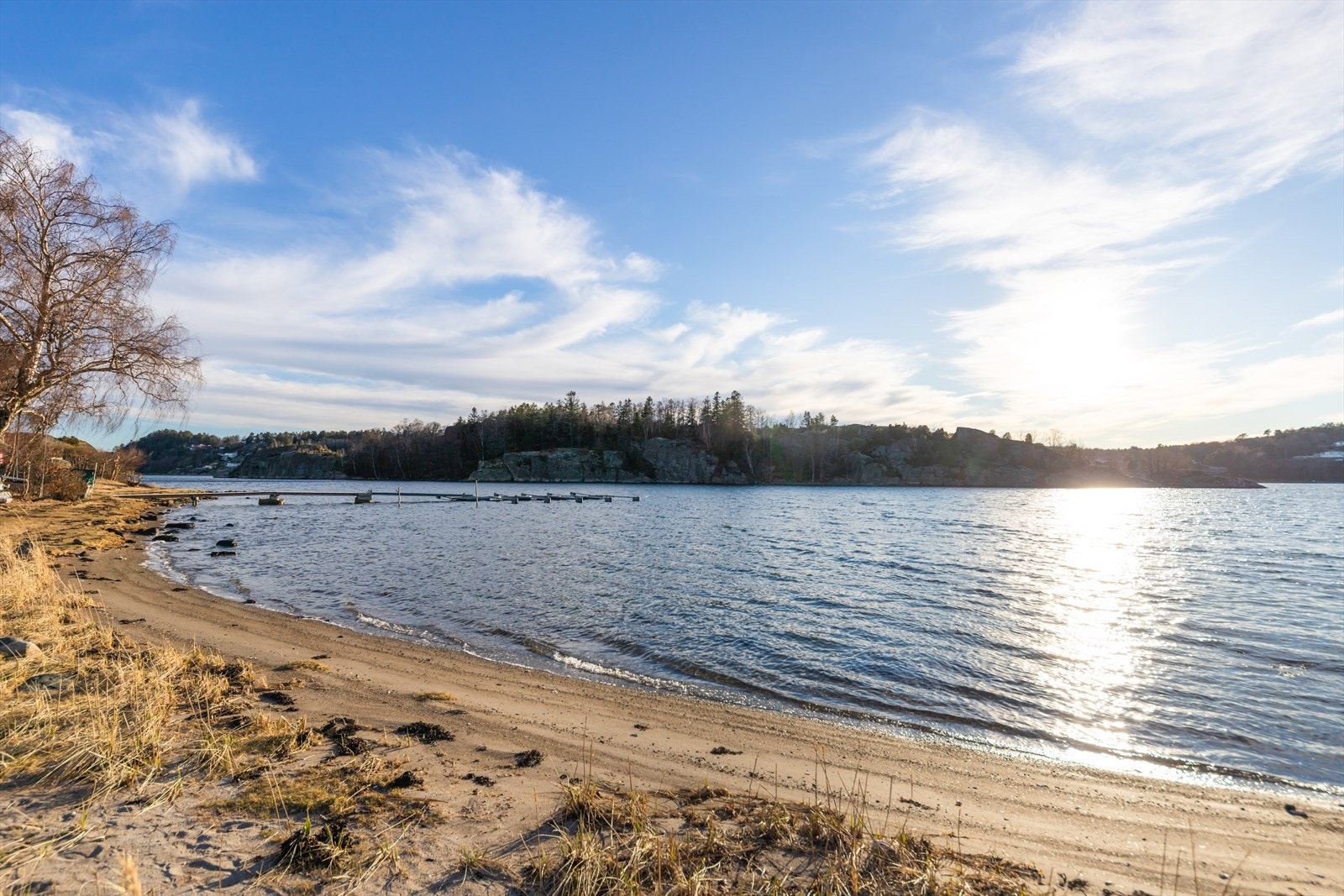 Kun 100 meter fra hytta er det en idyllisk sandstrand og egen båtplass ved en felles flytebrygge. Galleribilde