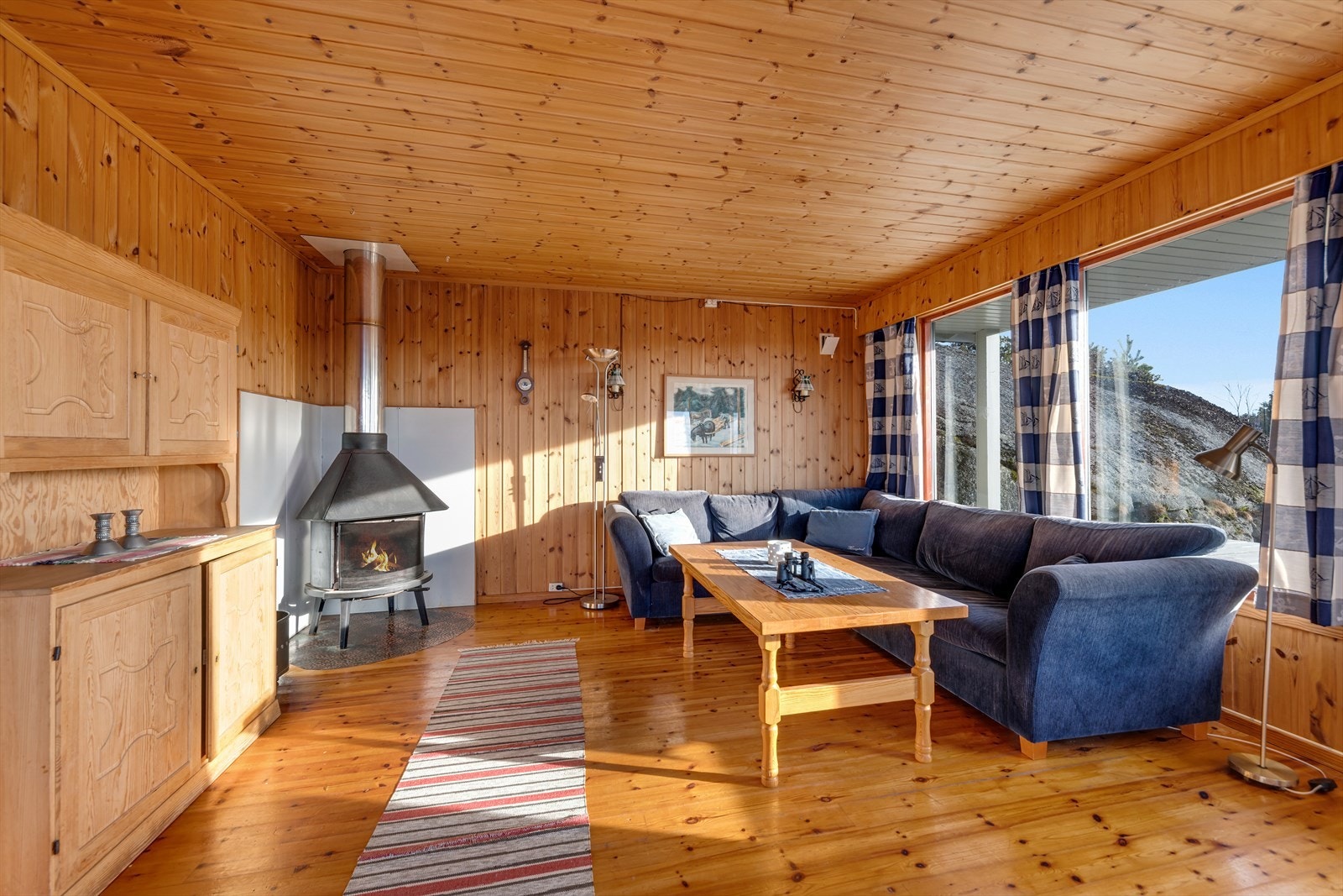 Etter en lang dag ute kan man komme inn å varme seg foran en vedovn i stuen. Galleribilde