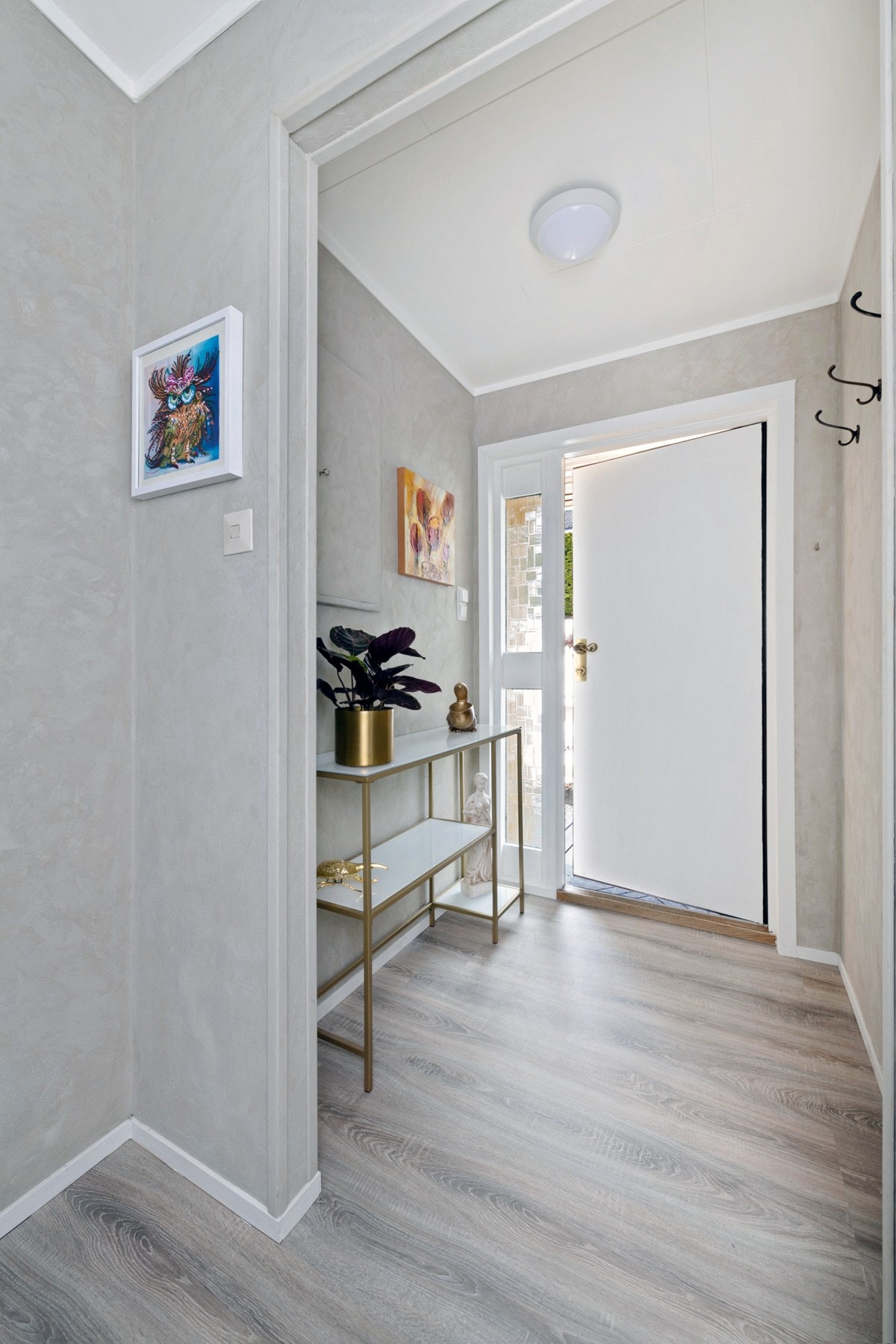 Entreen i første etasje har knaggrekke, moderne laminatgulv og lysegrå vegger. Galleribilde
