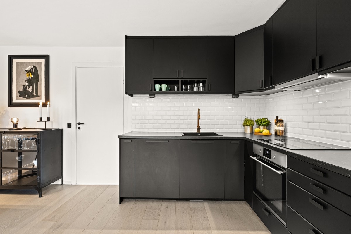 Kjøkkeninnredningen har sorte, matte fronter og laminert benkeplate med fliser over. Galleribilde