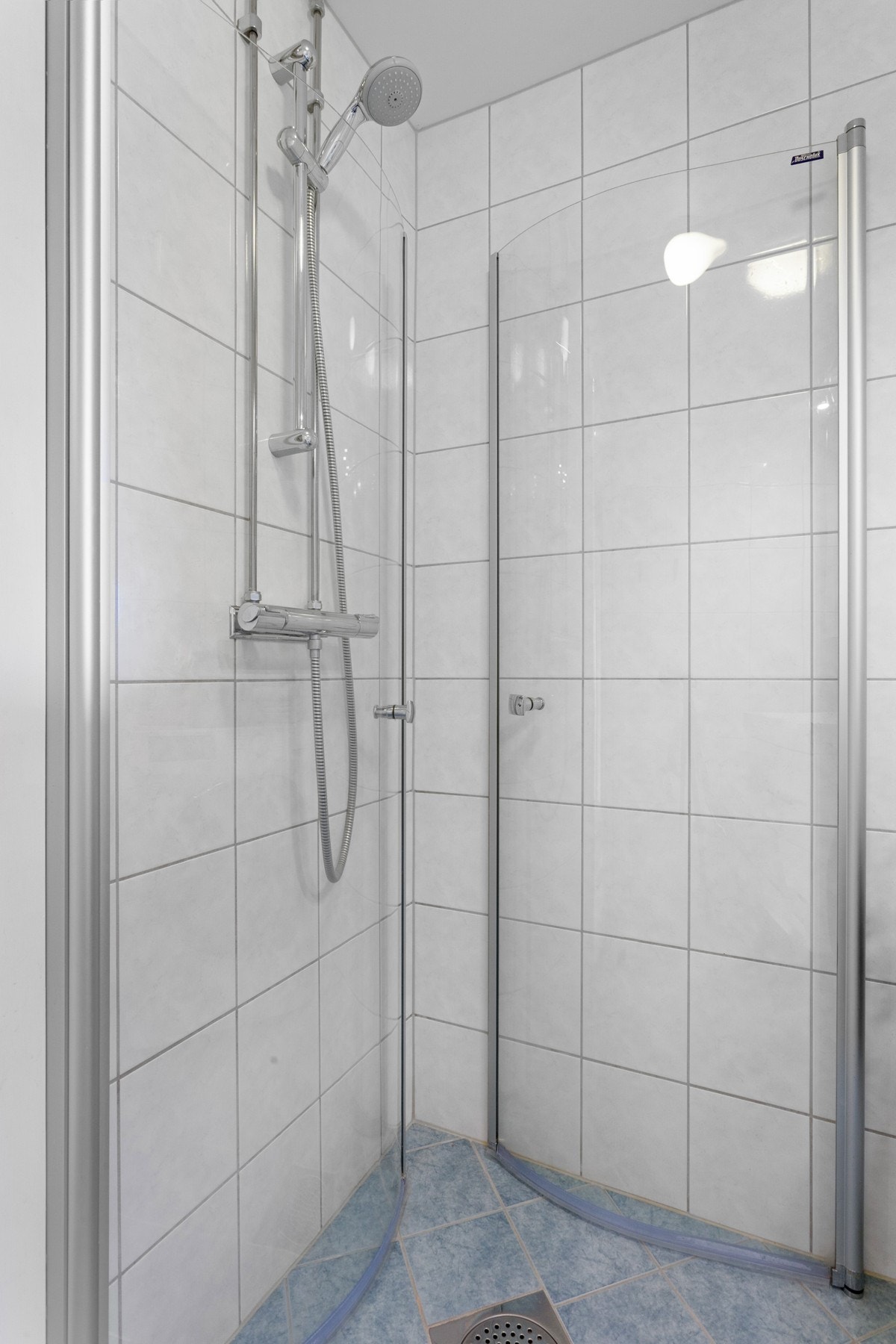 Badet har flislagte gulv med varme, flislagte vegger og opplegg for vaskemaskin Galleribilde