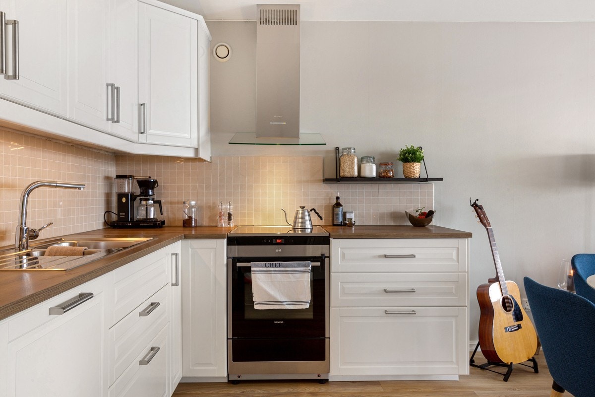 Kjøkkenet er pent med profilerte fronter og italienske mosaikkfliser over kjøkkenbenk. Galleribilde