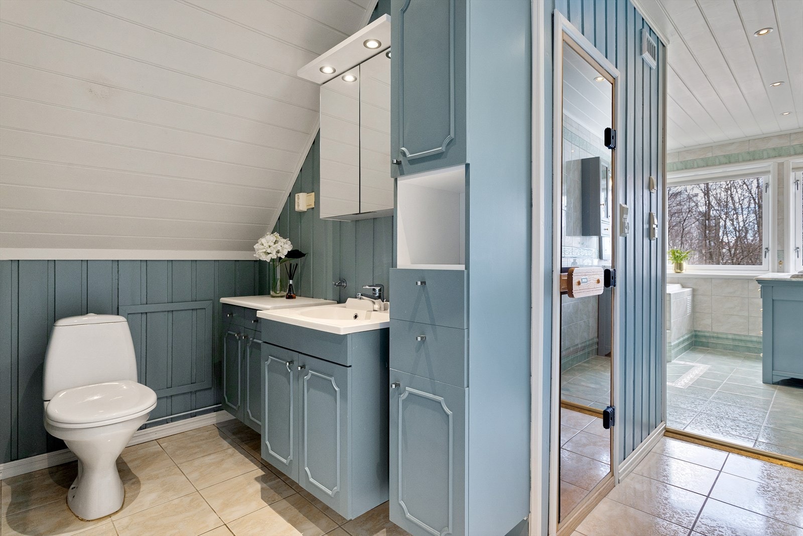 Stort flislagt baderom fra 2000 med varme i gulv. Baderommet består av toalettdel med innredning med glatte fronter og servanter med Oras ett-greps armatur samt to-greps armatur, speilskap med belysning og stikkontakter på vegg. Galleribilde