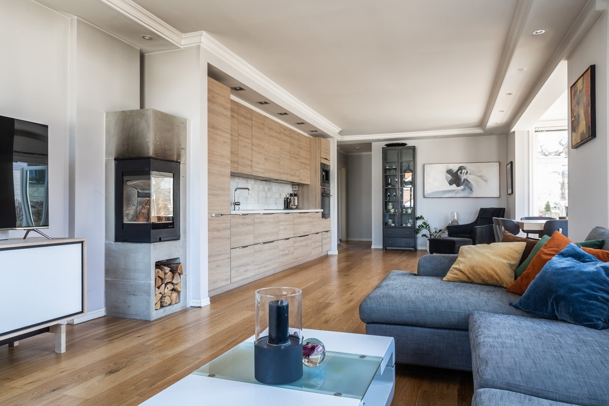 Stor stue med peis, i åpen løsning til kjøkkenet. Galleribilde