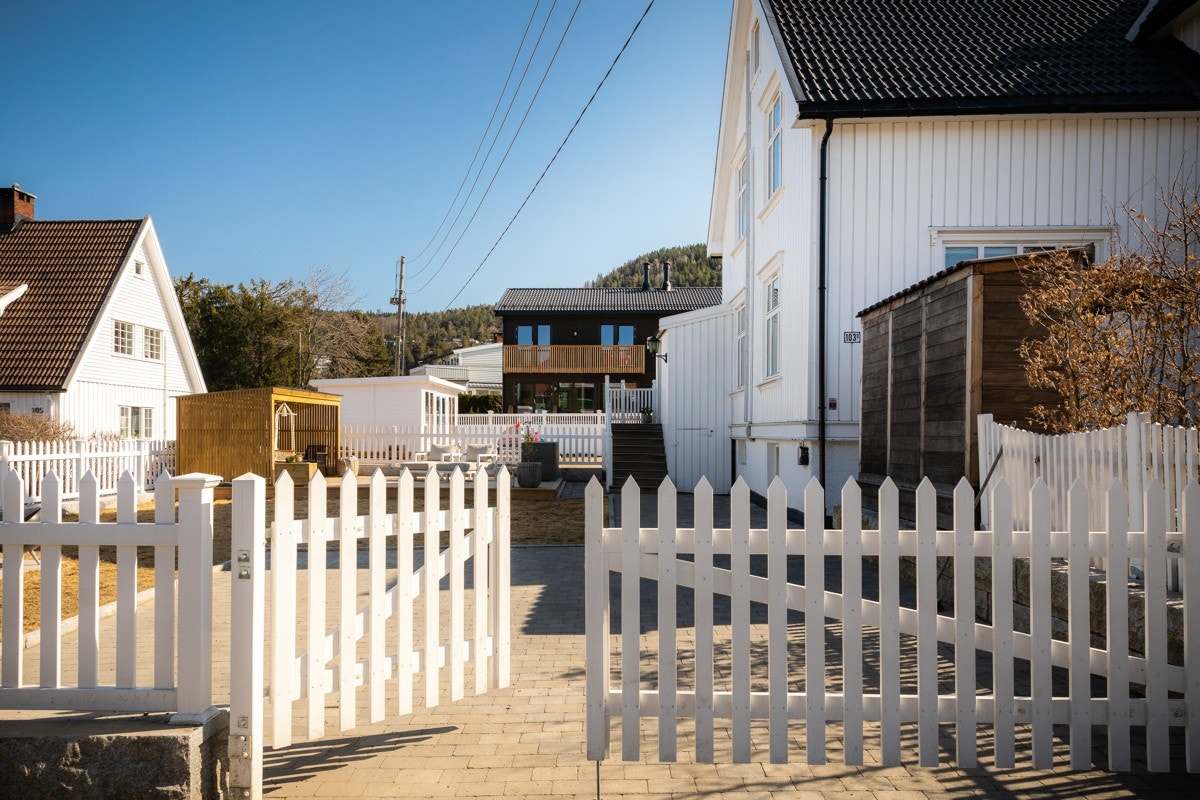 Port til brosteinsbelagt gårdsplass med el-bil uttak på hjørnet av huset. Galleribilde