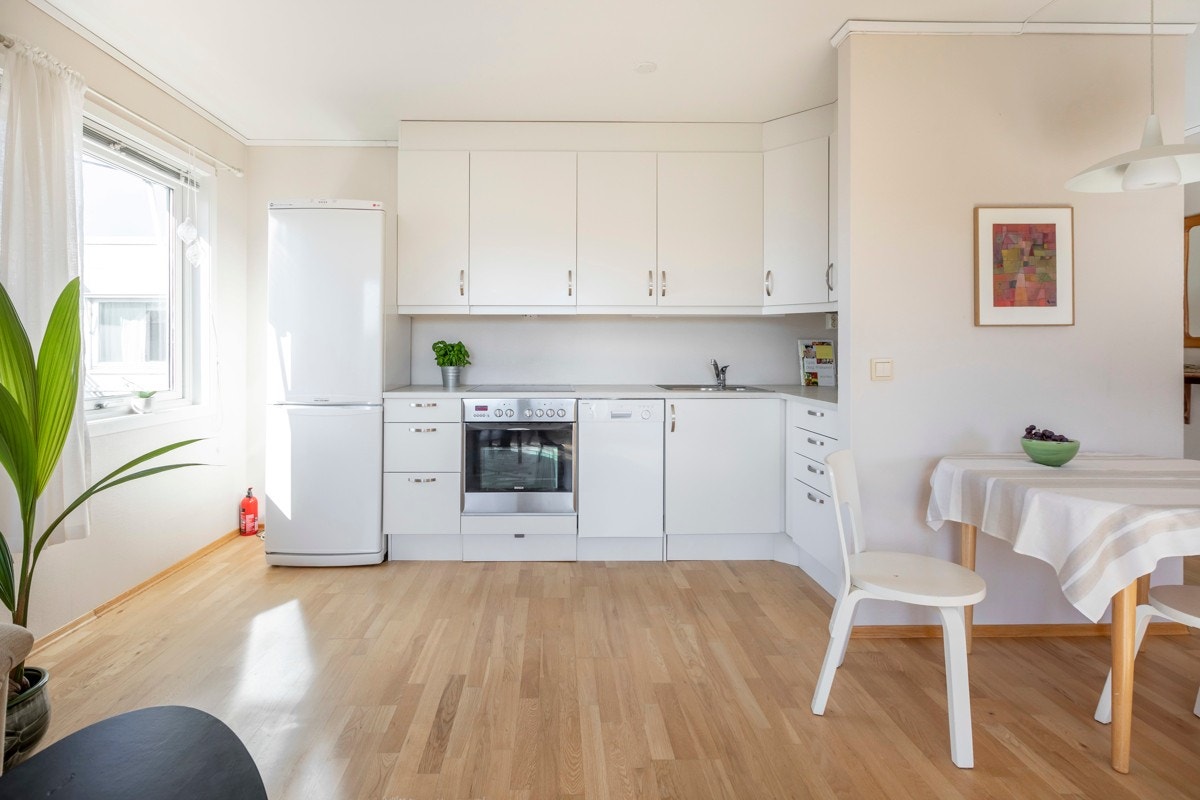 Kjøkkenet ligger med en åpen løsning mot stuen. Kjøkkeninnredningen har glatte fronter med lyslister og belysning under overskap. Galleribilde