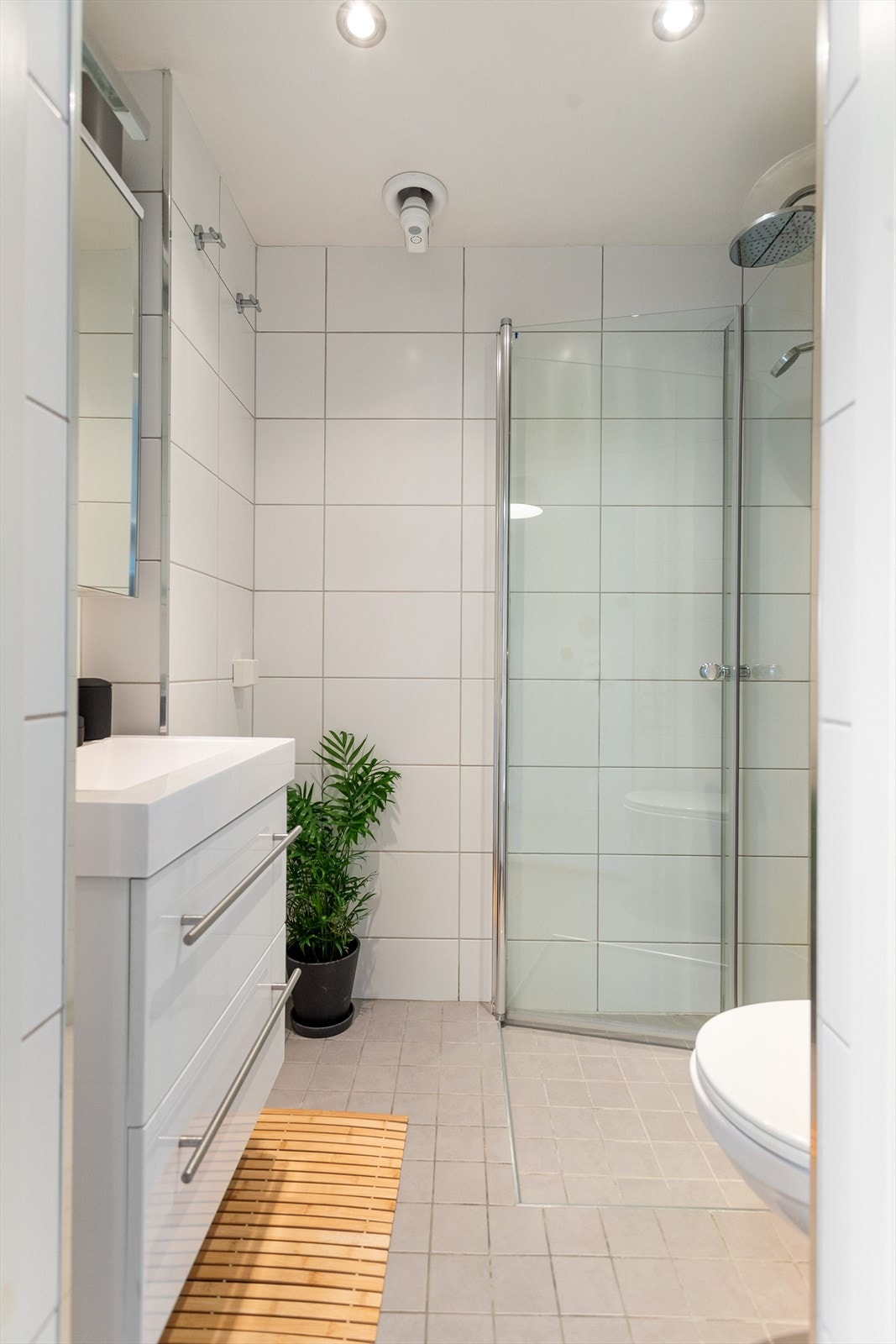 Baderom fra 2012 med flislagt gulv med gulvvarme og flislagte vegger. Opplegg for vaskemaskin. Det er også felles vaskeri i kjeller som er praktisk etter ferien. Galleribilde