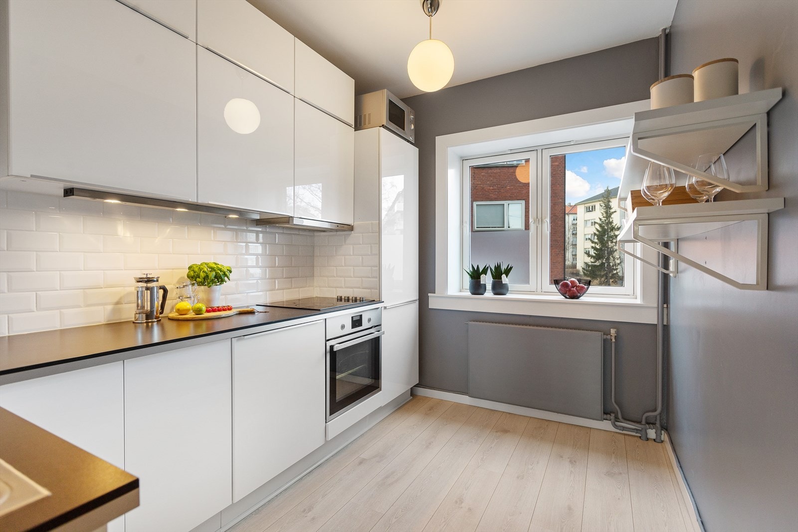 Kjøkkeninnredning med Ikea fronter fra 2015, innredning med glatte fronter i hvit utførelse, benkeplate av laminat og nedsenket oppvaskkum i rustfritt stål med ett-greps armatur. Det er plass til spisebord på kjøkken. Galleribilde