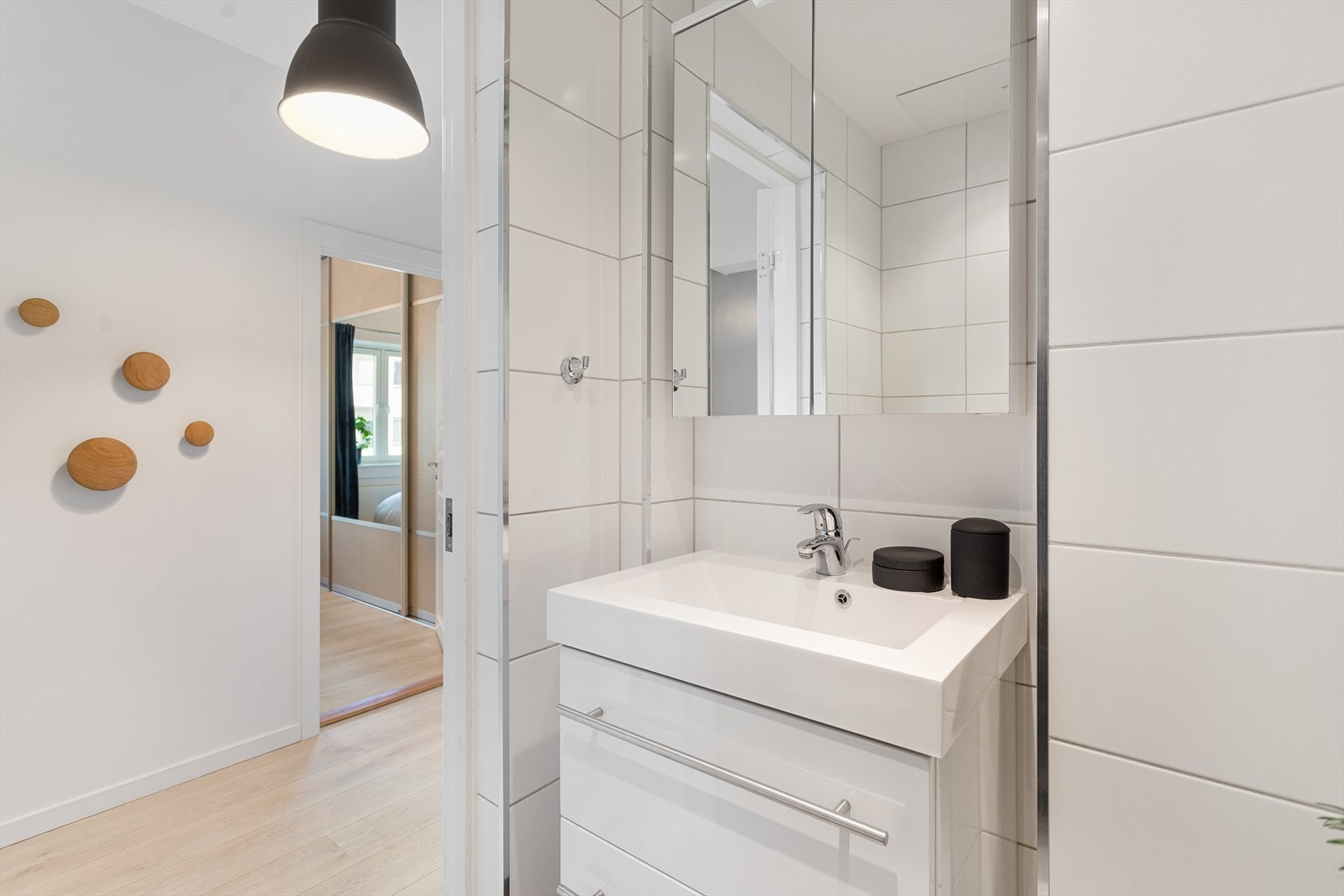 Nedsenket platehimling med downlight, vegghengt servantskap med ovenpåliggende servant og ett-greps armatur Hansgrohe samt speilskap med belysning over servant. Galleribilde