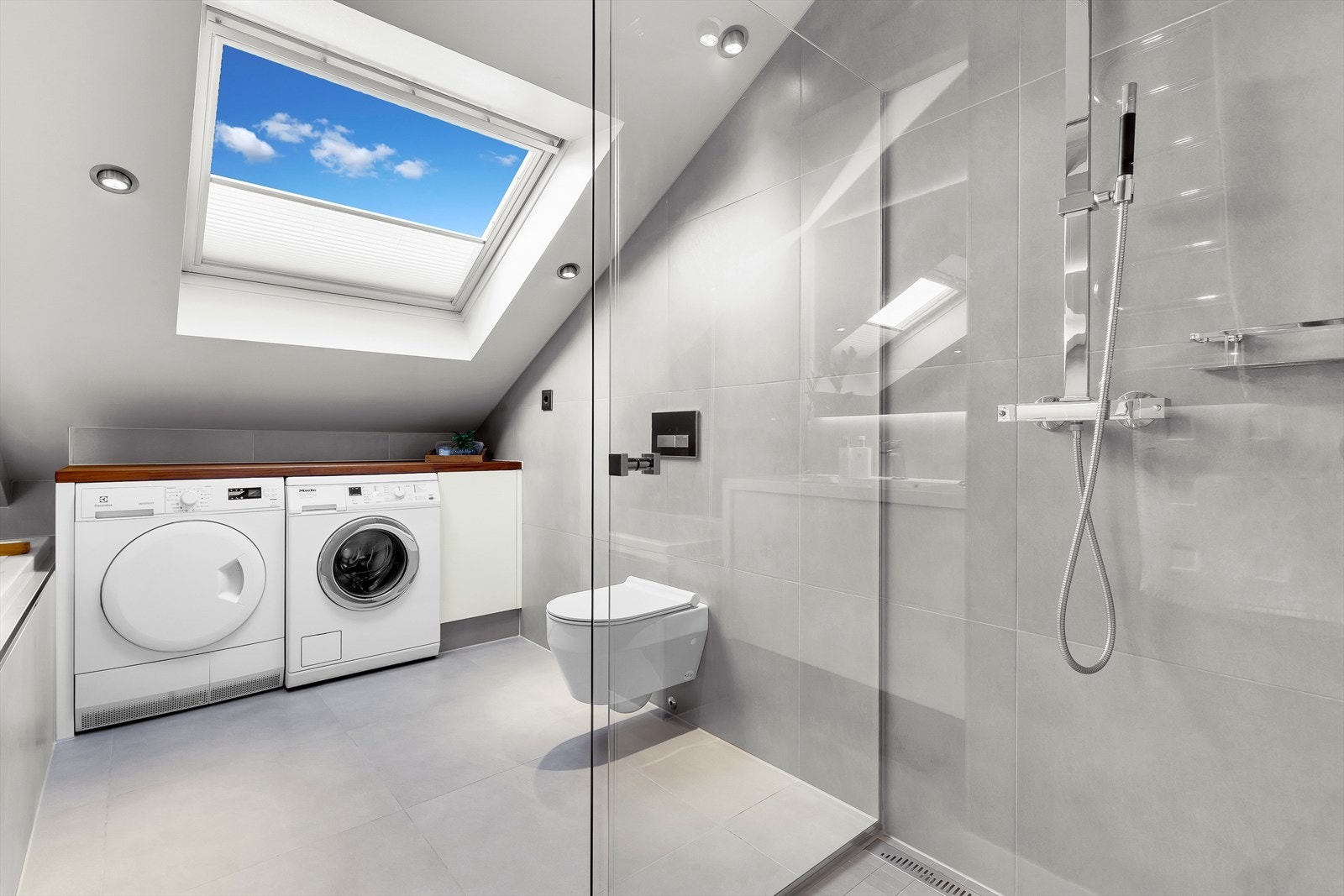 Bad med stor dusjsone, lekre fliser, vegghengt klosett og opplegg vaskemaskin og tørketrommel Galleribilde
