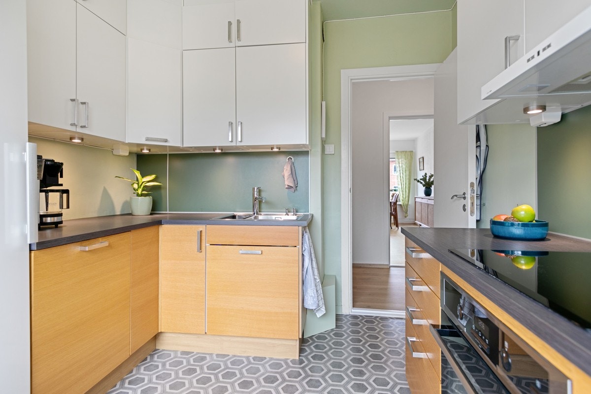 Ventilator med kullfilter, lys under overskap. Integrerte hvitevarer med komfyr, platetopp og oppvaskmaskin. Galleribilde