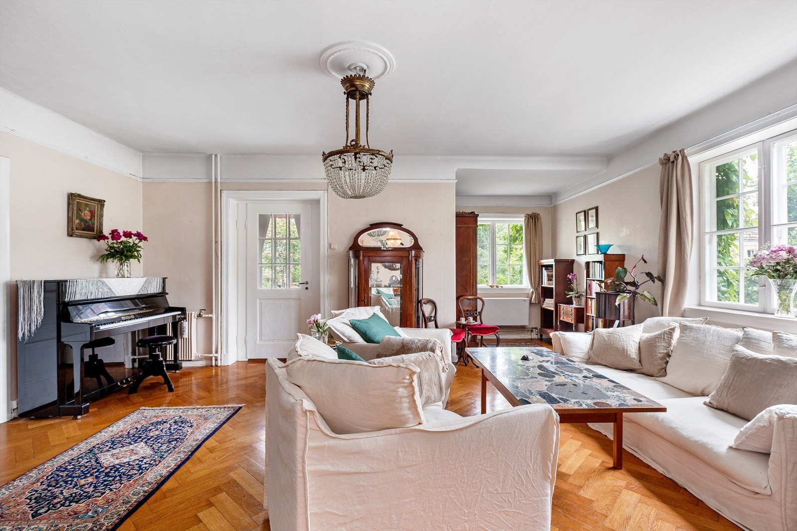 Stuen har store vinduer som gir fine lysforhold. Tiltalende fiskebensparkett på gulvene står fint til boligens stil. Galleribilde