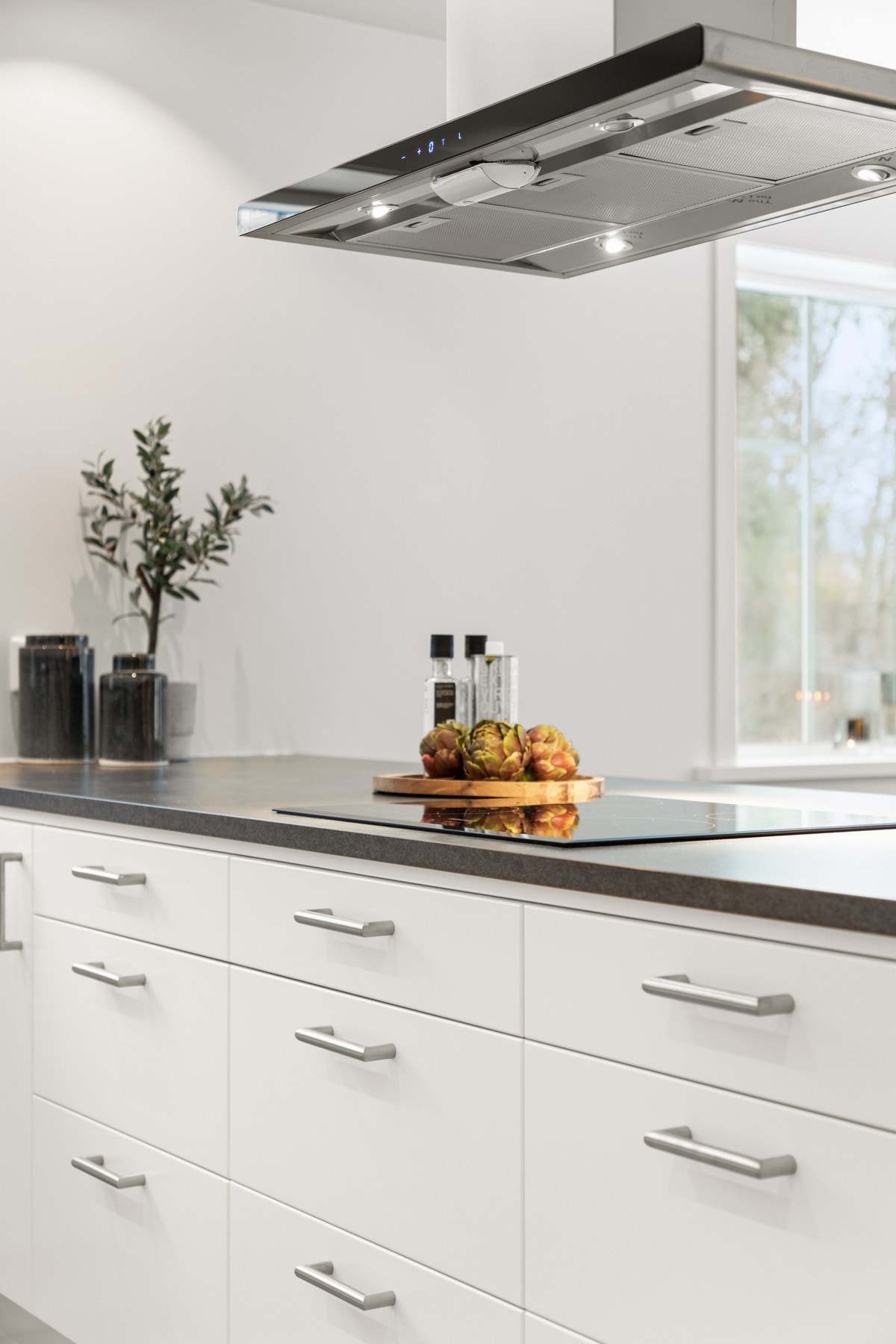 Kjøkkenøy med kokesone, fritthengende ventilator samt ekstra oppbevaringsplass. Galleribilde