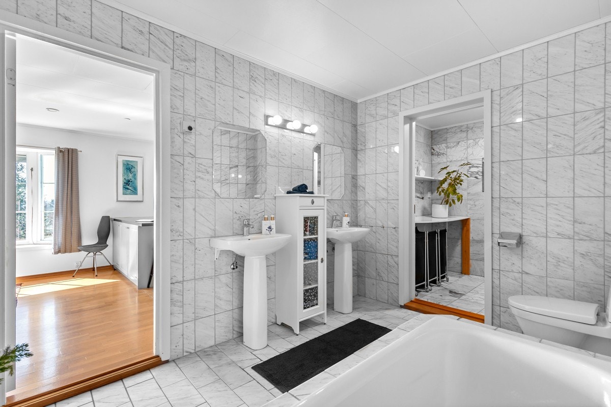 Stort baderom i 1. etg., innredet med søyleservant, toalett og innmurt badekar med flislagt front Galleribilde