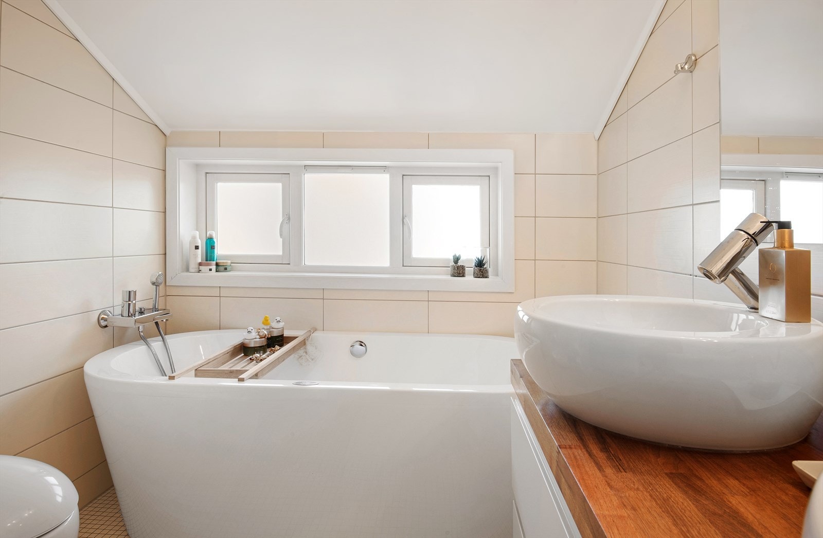 Pent baderom med frittstående badekar og dusjnisje med dør i herdet glass. 2 stk. servanter. Speil og lys over servanter. Vegghengt toalett. Galleribilde