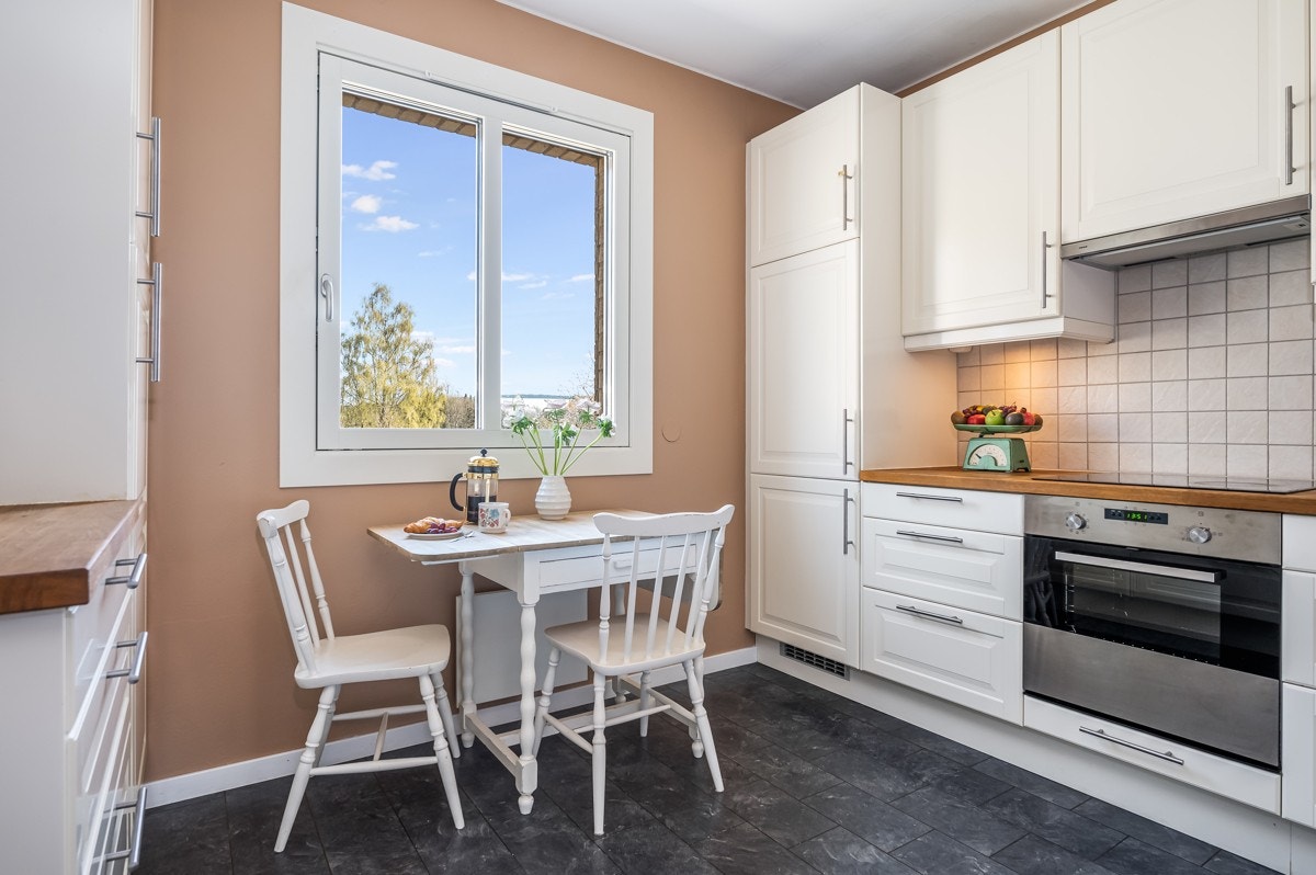 Kjøkkenet er malt i en varm fargetone, og det er lagt grå laminatfliser på gulvet. Galleribilde