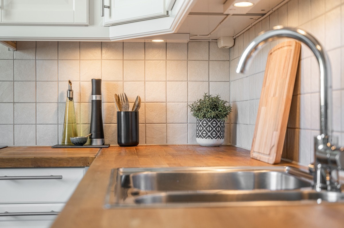 Over kjøkkenbenken er det lyse fliser og god arbeidsbelysning. Galleribilde