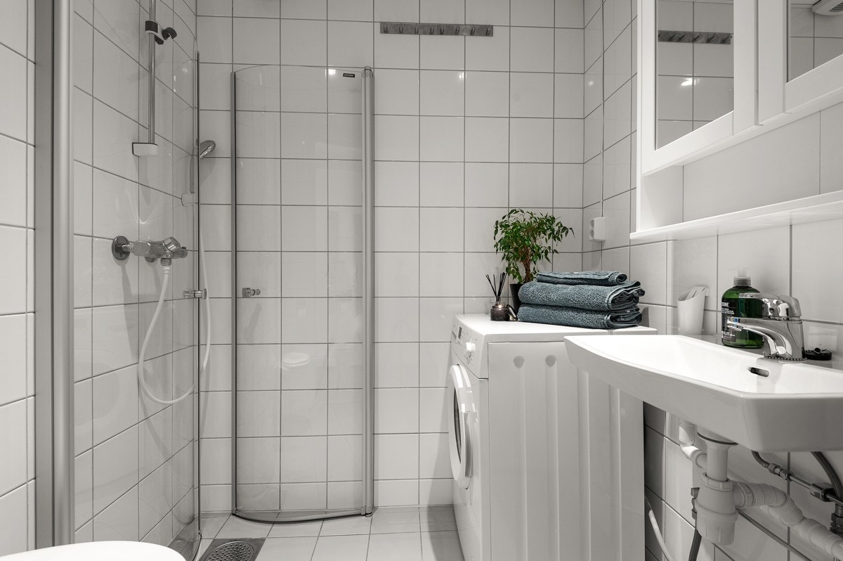 Baderommet har lysegrå fliser på gulv med gulvvarme, hvite fliser på veggene og downlights i himlingen. Galleribilde