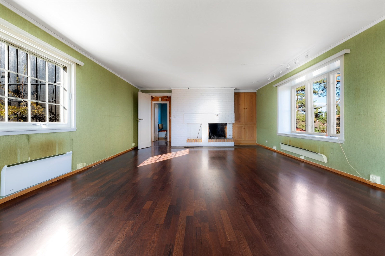 Åpen og stor stue i første etasje med naturlig lys fra 3 yttervegger. Her er det utgang til terrasse og hage. Åpen peis sentralt i rommet Galleribilde