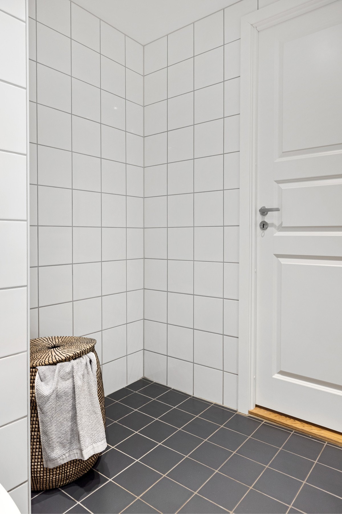 Baderommet har opplegg for vaskesøyle (vaskemaskin og tørketrommel), termostatstyrte varmekabler i gulv, mørke fliser på gulv og lyse vegger, samt senket himling med innfelte downlights. Galleribilde