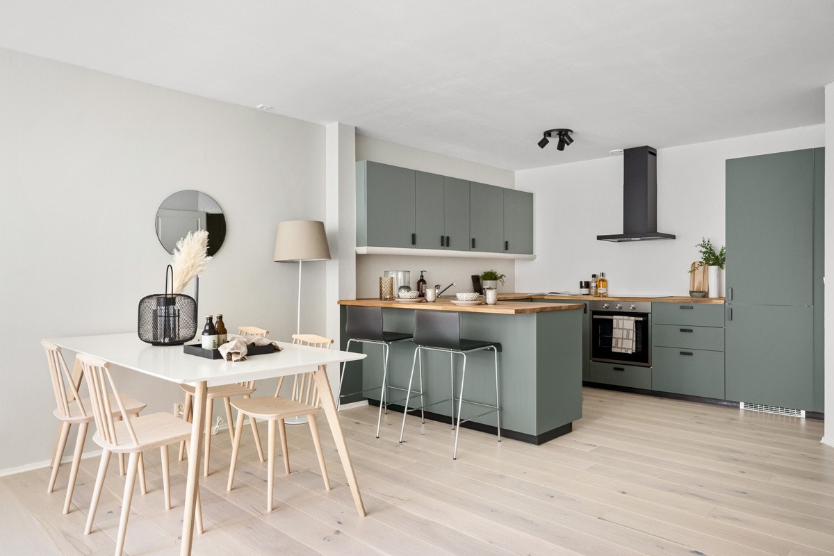 Kjøkkeninnredningen har gode oppbevaringsmuligheter i over- og underskap, fronter i en delikat grønnfarge, heltre benkeplate med nedfelt kum i rustfritt stål og ettgreps blandebatteri. Galleribilde