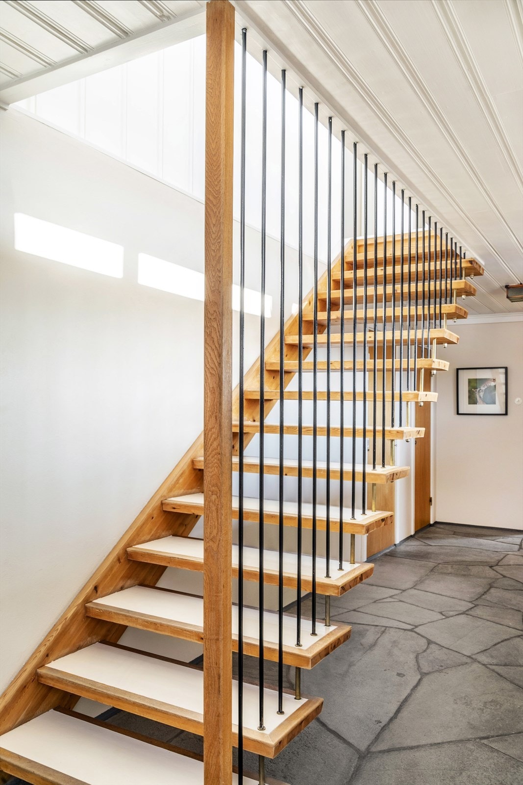 Hall/gang med skiferfliser på gulv og malte flater ellers. Fra hall er det en lekker, tidsriktig trapp opp til boligens hovedetasje. Galleribilde