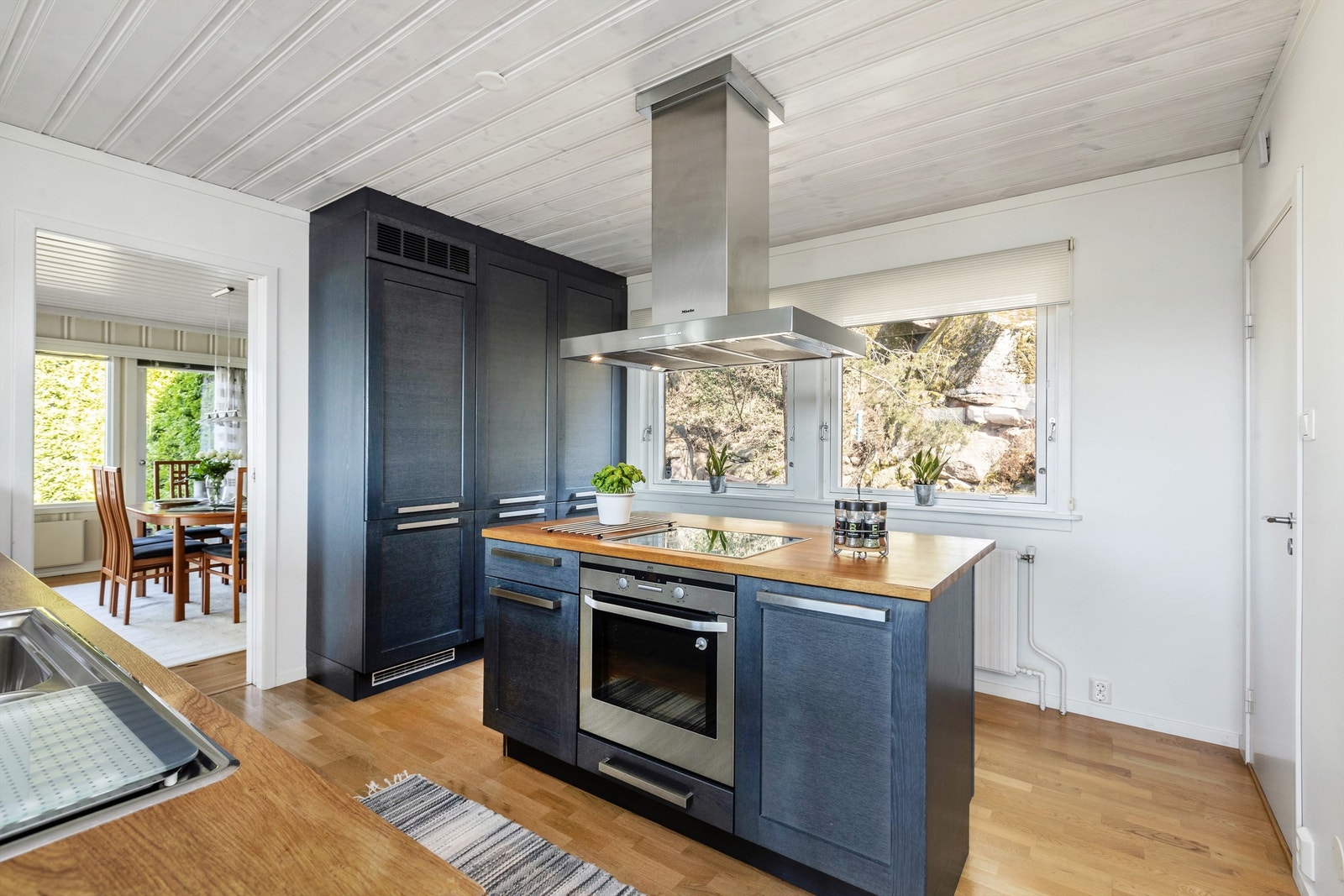 Mørke fronter i heltre eik og heltre benkeplater i eik. Kjøkkenet har god skap- og benkeplass og har en kokeøy med koketopp og stekeovn fra AEG og takhengt ventilator fra Miele. Galleribilde